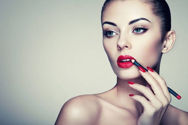 Beautiful woman paints lips with lipstick - Photo, Image
