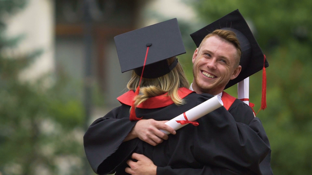 Молодые выпускники обнимаются после церемонии вручения дипломов, красивые улыбающиеся люди
 - Кадры, видео