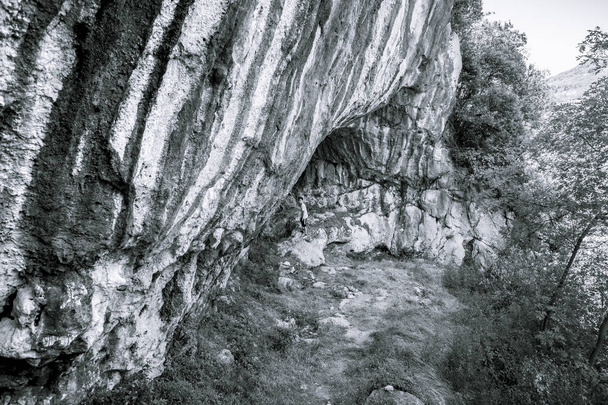 adolescente de pie en la entrada de una enorme cueva
 - Foto, Imagen