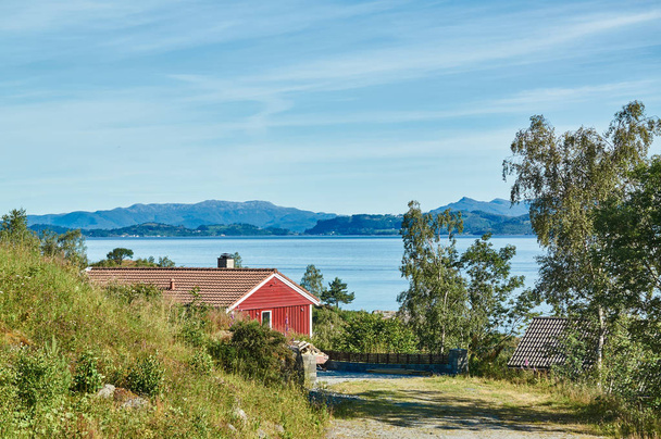 岩の間の赤い夏の別荘フィヨルド - 写真・画像