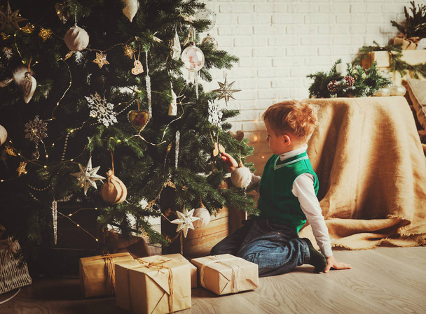 Μικρό αγόρι στολίζει χριστουγεννιάτικο δέντρο - Φωτογραφία, εικόνα