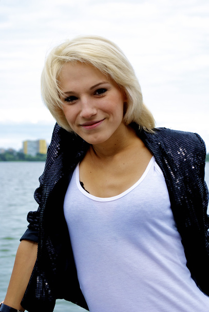 Beautiful blond caucasian model girl in black jacket and jeans shorts - 写真・画像