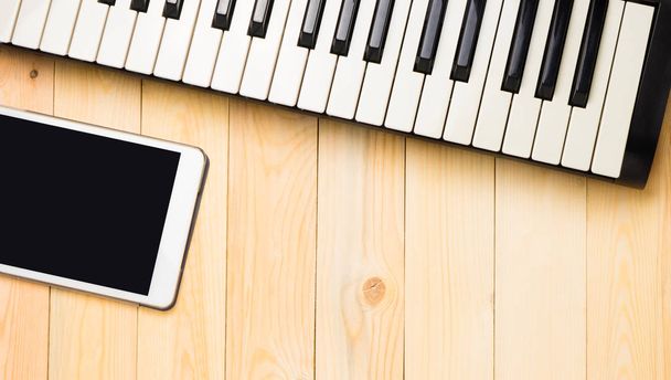 Teclado musical com tablet sobre fundo de madeira
 - Foto, Imagem