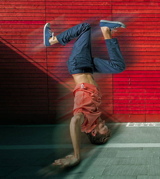 Break dancer doing handstand against colorful wall background - 写真・画像