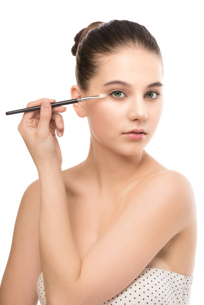 Young brunette woman with clean face. Girl perfect skin applying cosmetic brush. Isolated on a white. - Фото, изображение