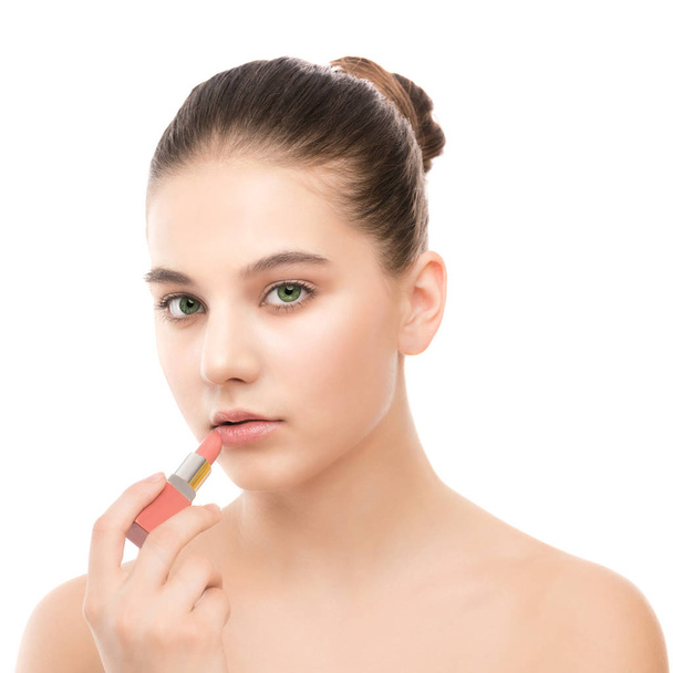 Young brunette woman with perfect clean face applying lipstick. Isolated on a white. - Fotoğraf, Görsel