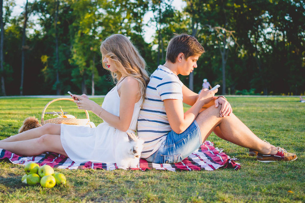Young beautiful couple resting in the park and using smarphones - Photo, image