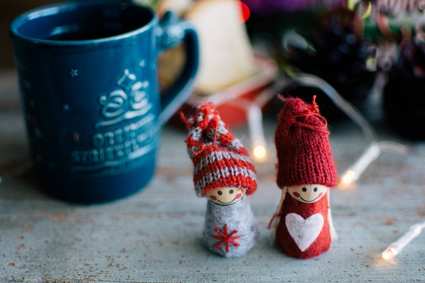 Due bambole in maglia e una tazza di caffè con sfondo natalizio
 - Foto, immagini