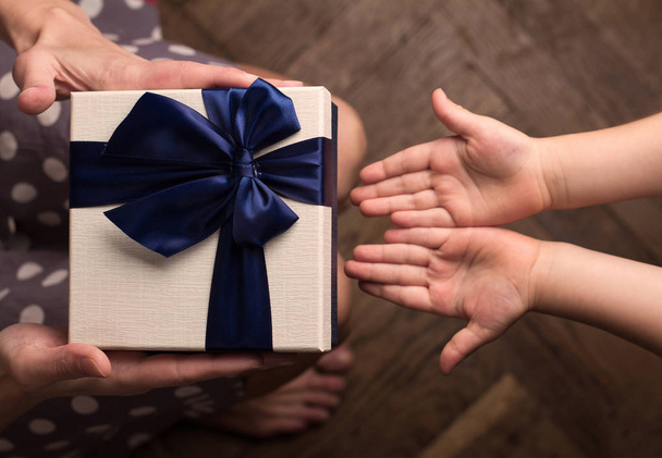 Mother giving a big gift boxes to her kid with open hand - Photo, image