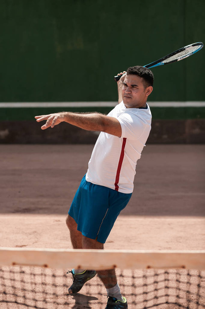 Handsome young man on tennis court. Man playing tennis. Man hitting tennis ball - Photo, Image