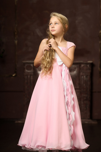Beautiful young blonde girl with long hair in a pink princess dress. - Foto, imagen