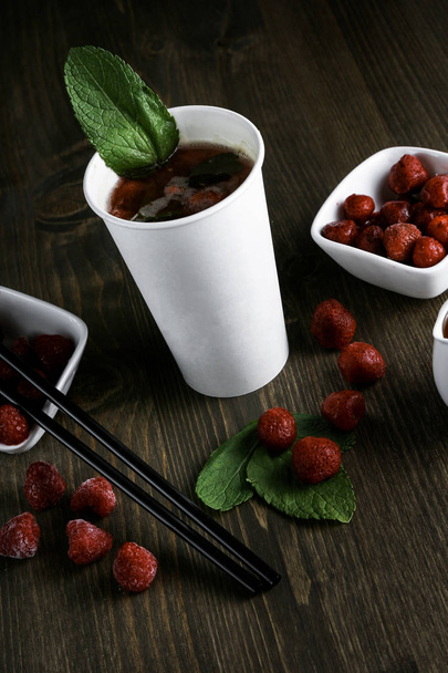 Drink in a white cup with strawberries and mint on a wooden background - Фото, зображення