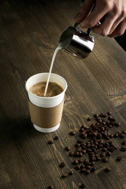 The hand that pours milk into cup of coffee - Foto, afbeelding