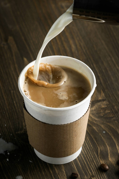 Tasse Kaffee, der auf Milch gegossen wird - Foto, Bild