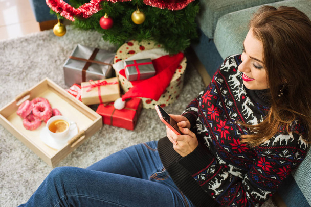 Young smiling woman typing message with mobile phone on Christmas - Foto, Bild