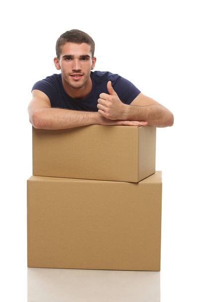 a young man with a box shows the finger to the top - Photo, Image