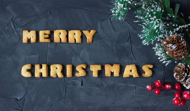 christmas background with branch of christmas tree with baked gingerbread words merry christmas . creative idea - 写真・画像