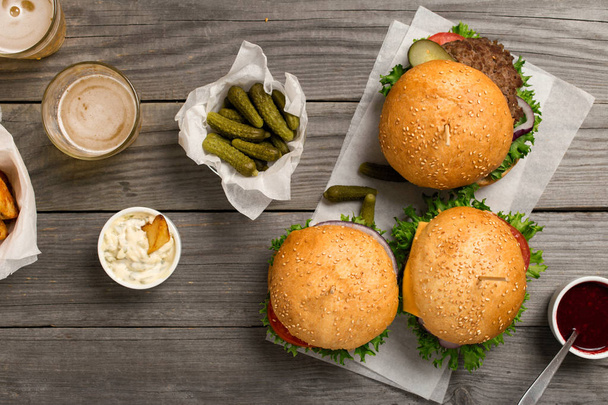 Burgers and cheeseburger on wooden table with sauces and beer - Φωτογραφία, εικόνα