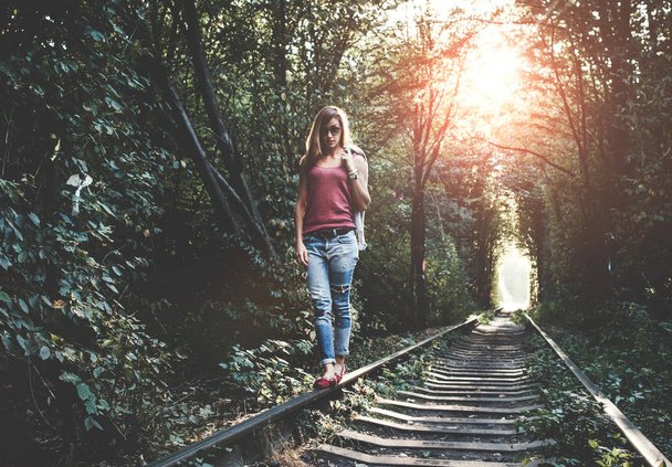 Beautiful young woman walking on the rails in the evening - Fotoğraf, Görsel