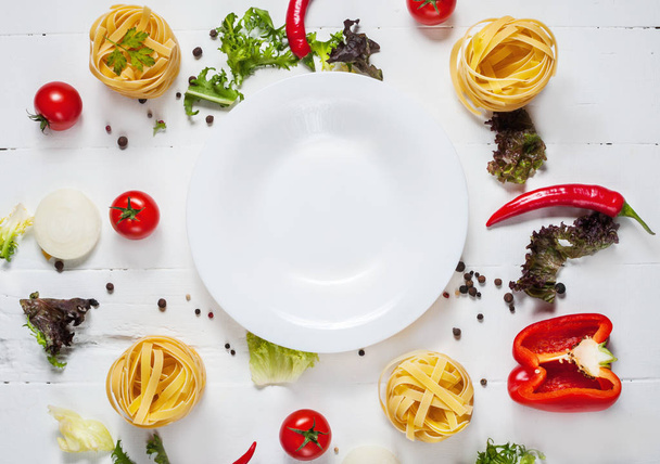 Інгредієнти для приготування спагетті, вишневі помідори, перець навколо білої тарілки розмістити текст, рамка на дерев'яному сільському фоні вид зверху
 - Фото, зображення