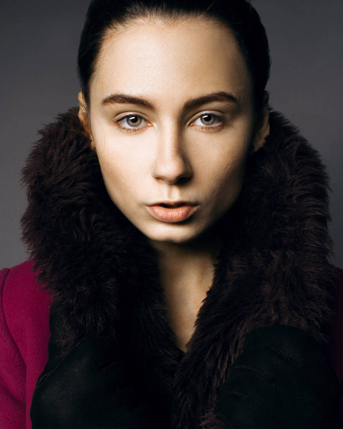 Serious portrait of a girl in a fur coat in the studio - Fotó, kép