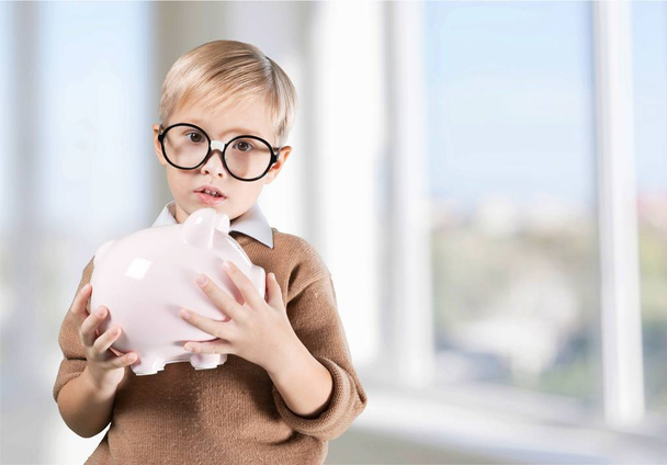 thoughtful boy holding piggybank - Фото, изображение