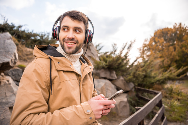Man in headphones holding smartphone - Photo, Image