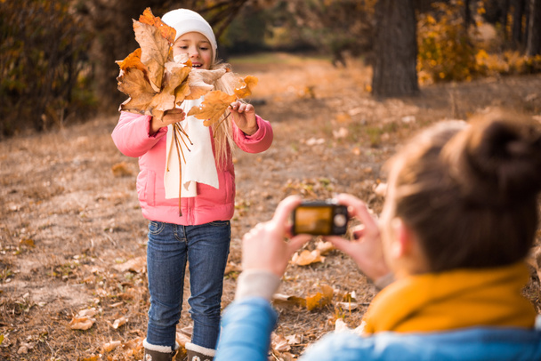 Moeder fotograferen dochter in herfst park - Foto, afbeelding