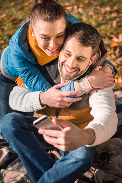 schönes lächelndes Paar schaut aufs Smartphone - Foto, Bild
