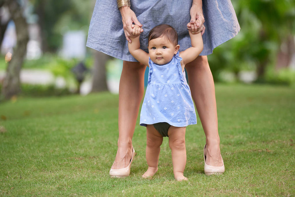 girl making first steps with mother - Foto, Imagen