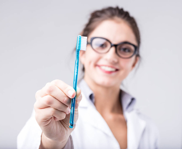 Mujer sonriente sosteniendo un cepillo de dientes
 - Foto, imagen