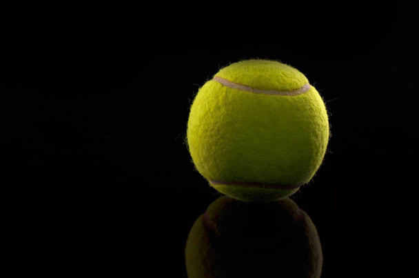 Tennis ball on black background - 写真・画像