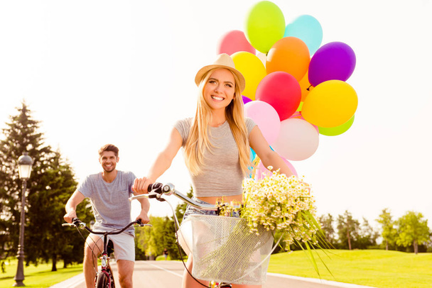 Portrait of beautiful woman with balloons and flowers riding bik - Foto, Imagen