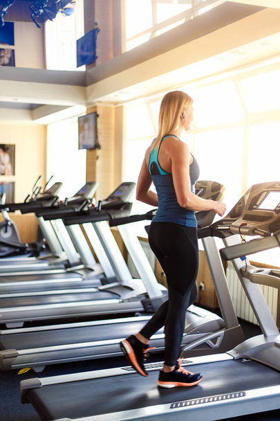 Young woman at the gym exercising. Run on a machine. - Foto, Imagen