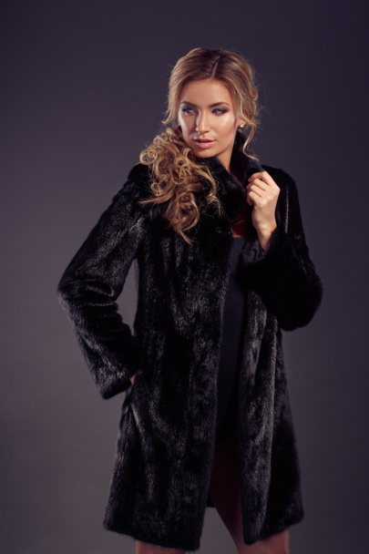 Portrait of beautiful blonde woman in black fur coat - Фото, изображение