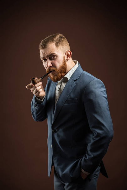 Elegant man with beard holding smoking pipe - 写真・画像