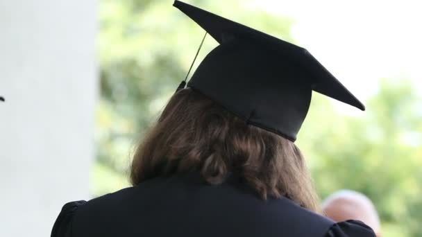 Estudiante graduado en vestido académico hablando con amigos después de la concesión del diploma
 - Imágenes, Vídeo