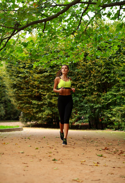 Young woman running in green park, fitness outdoor - Foto, afbeelding