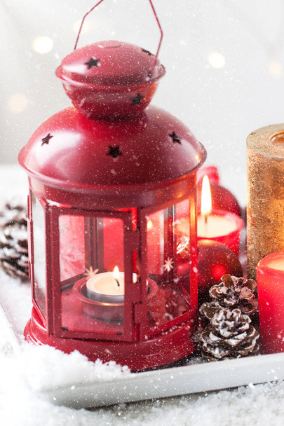 Різдвяний ліхтар зі свічками, снігом, різдвяними прикрасами та ялиновими шишками. Новорічна, святкова або зимова концепція
. - Фото, зображення