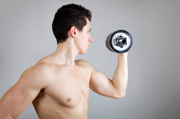 Muscular man lifting weights. Side view. - Foto, Imagen