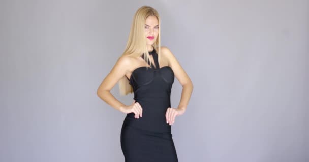 Sexy blond modelka pózuje ve večerních šatech nad šedá - Záběry, video