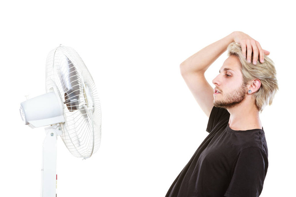 Young man fighting with wind from cooling fan - Photo, image