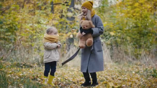 Gesundes Familienkonzept - kleines blondes Mädchen mit Mama verbringt Zeit im Herbstpark - Springen und Spaß haben - Filmmaterial, Video