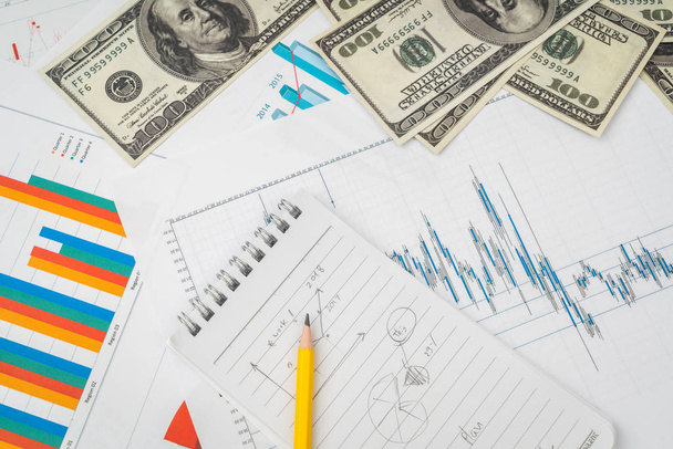 Фінансові графіки на столі з банкнотами доларів
 . - Фото, зображення