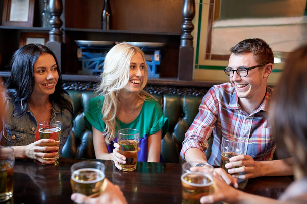 happy friends drinking beer at bar or pub - 写真・画像