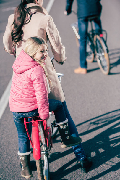 Cheerful family biking in park  - Zdjęcie, obraz