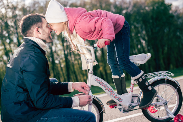 Father checking bicycle of little daughter  - Foto, afbeelding