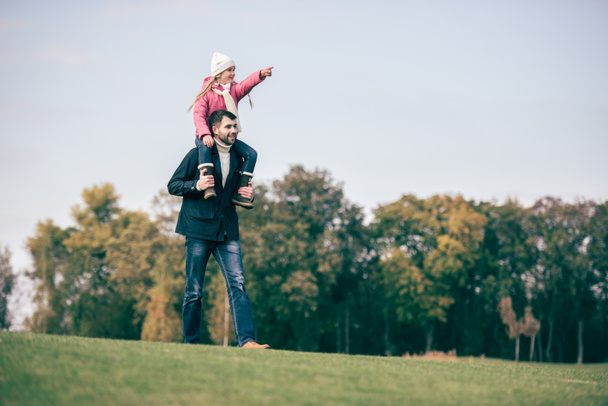Улыбающийся отец носит дочь на плечах
 - Фото, изображение