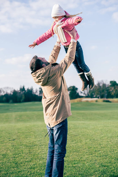 Father holding daughter and playing in park - Fotografie, Obrázek