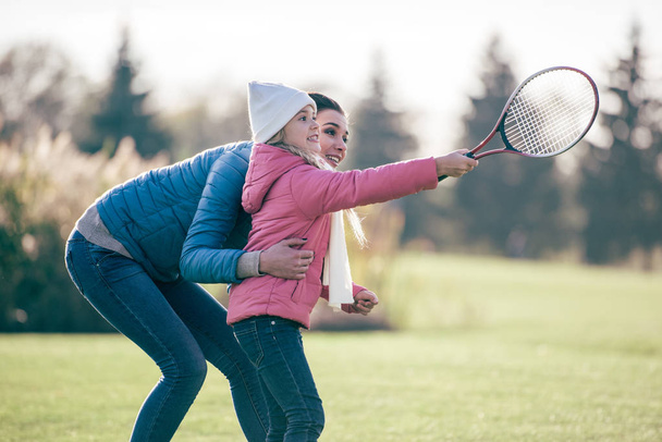Sorridente madre con figlia giocare badminton
 - Foto, immagini